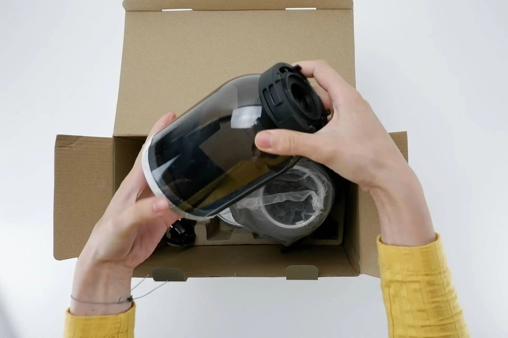 Unboxing mlýnku s mlecími kameny Na obrázku redaktorka vytahuje z krabice mlýnek s mlecími kameny.