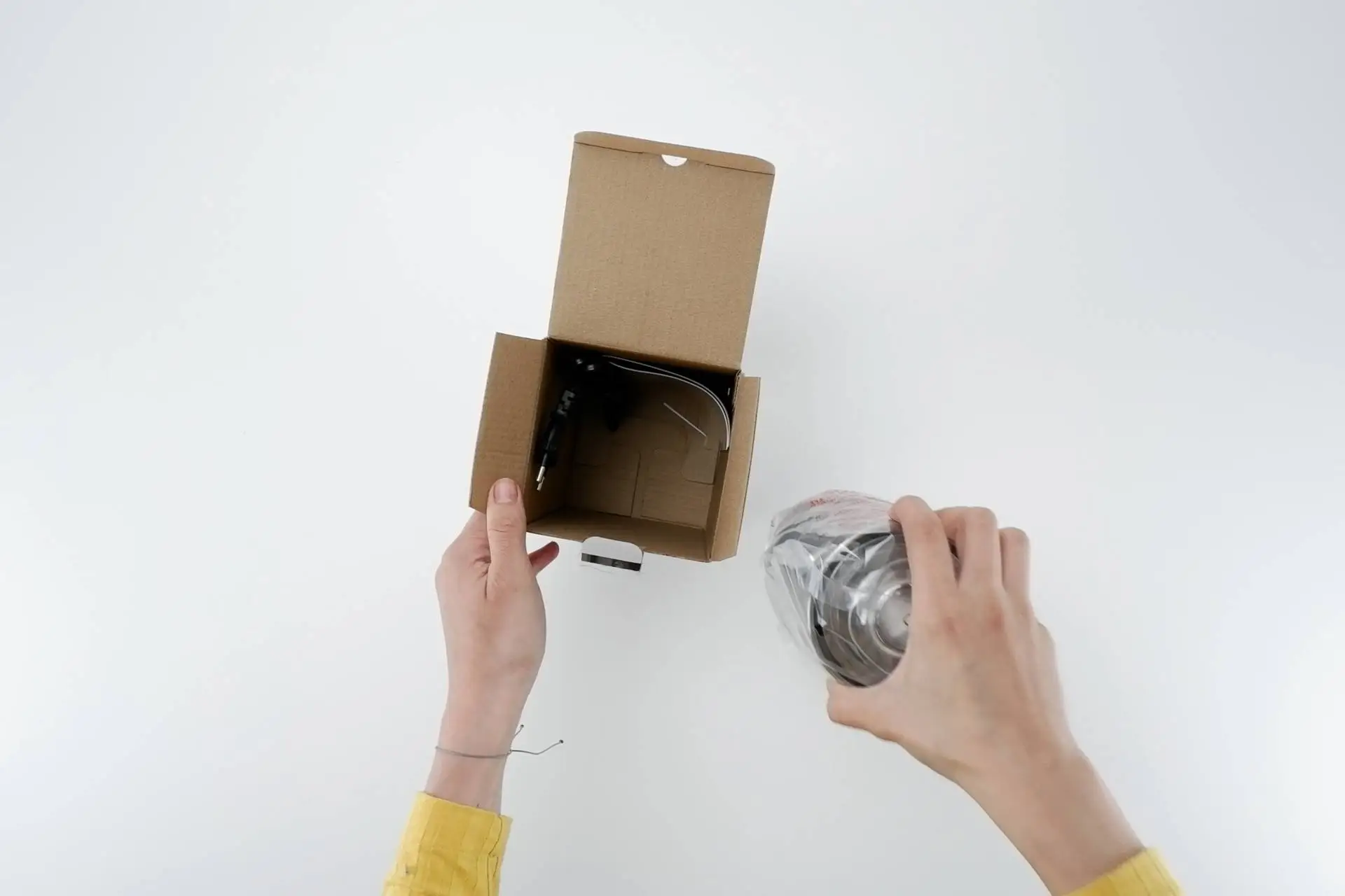 Unboxing mlýnku s tříštivým nožem Na obrázku redaktorka vytahuje z krabice mlýnek s tříštivým nožem.