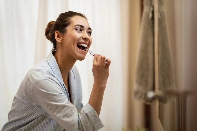 Happy woman cleaning her teeth with a toothbrush in the morning.