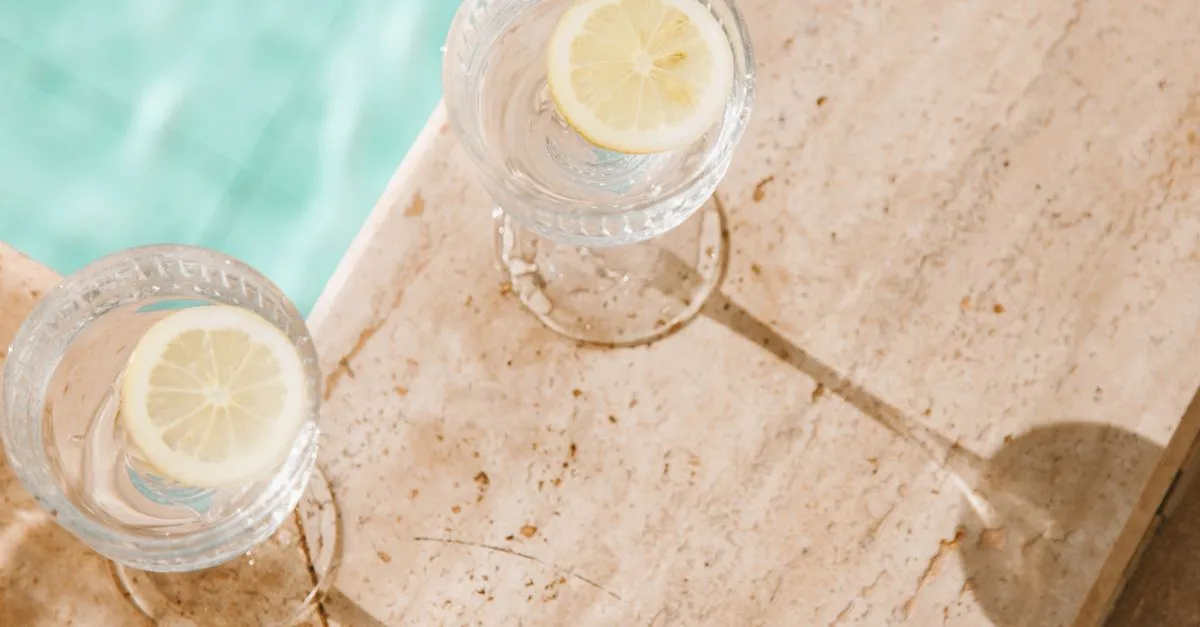 Dvě sklenice vody s plátky citronu u bazénu