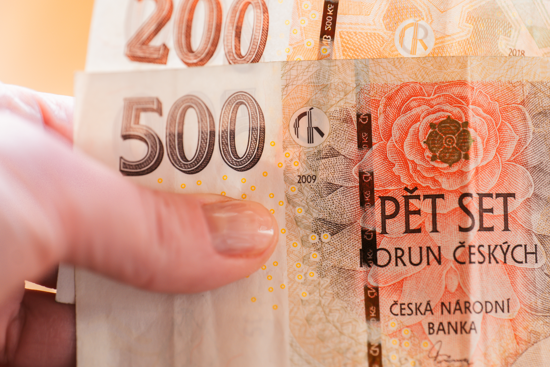 České bankovky 200 a 500 korun v ruce