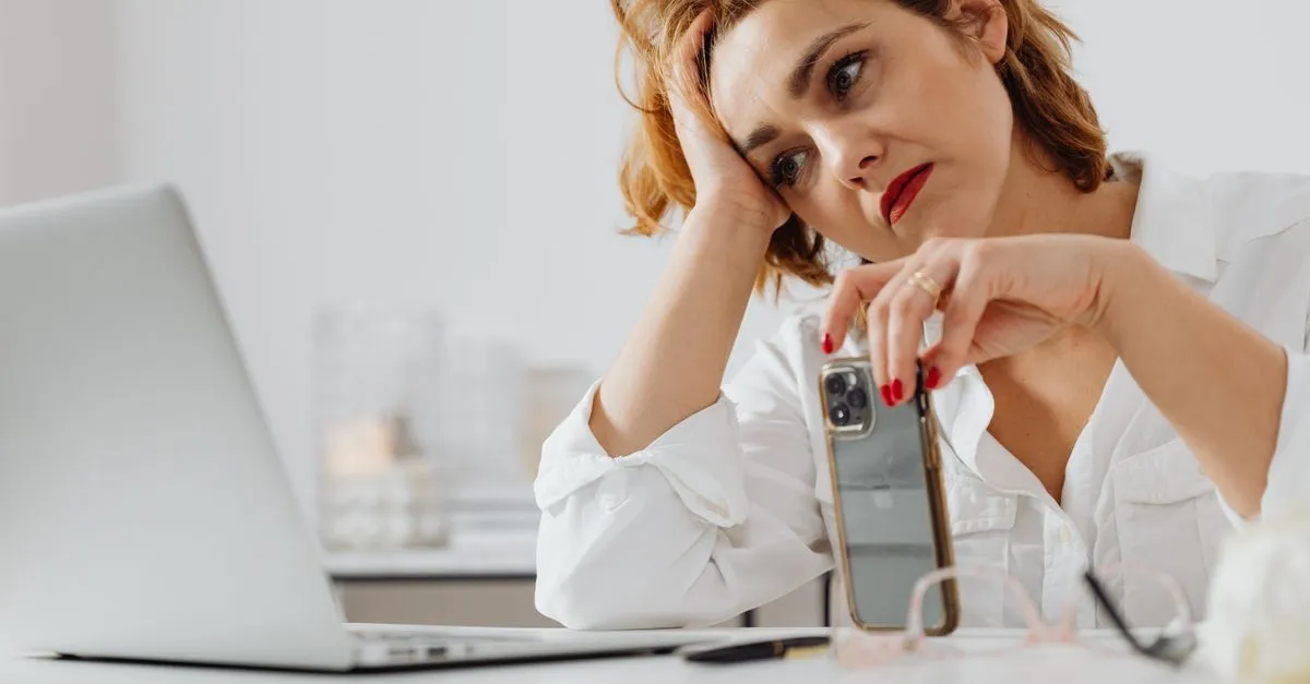 Žena si nedůvěřivě prohlíží zprávu v mobilu