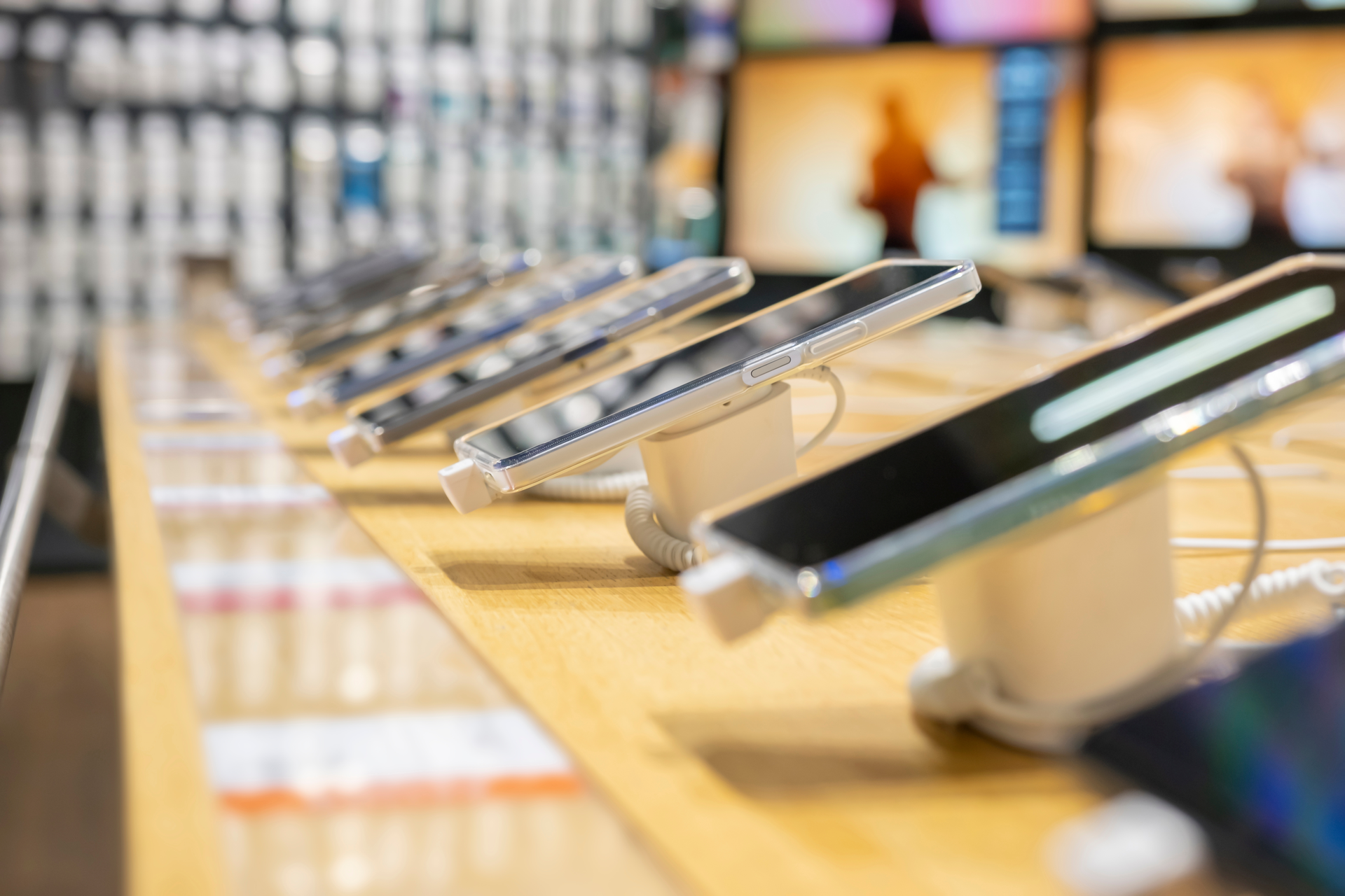 Řada chytrých telefonů na prodejních stojáncích v obchodě