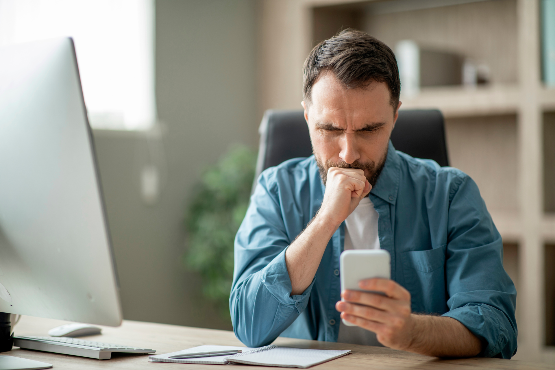Muž nedůvěřivě zkoumá zprávu v telefonu