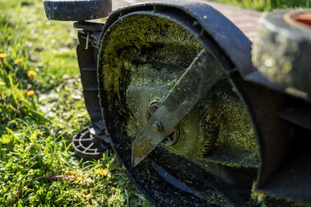 Detail spodku sekačky zaneseného nalepenou mokrou trávou
