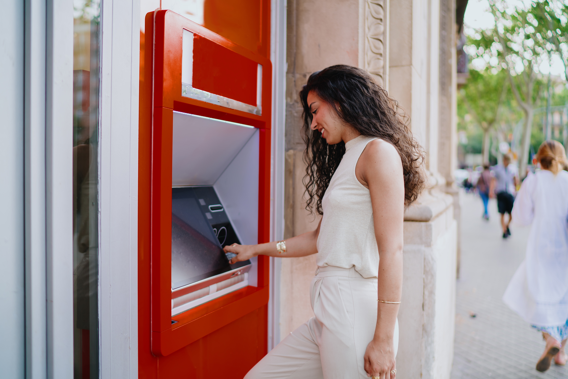 Žena vybírá peníze z bankomatu na ulici