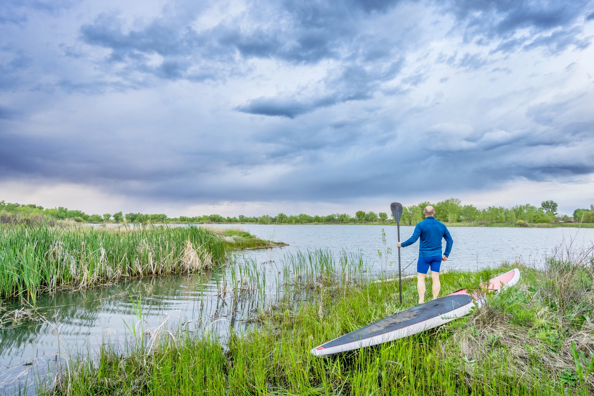 Paddleboardista sleduje bouřkovou oblohu nad jezerem