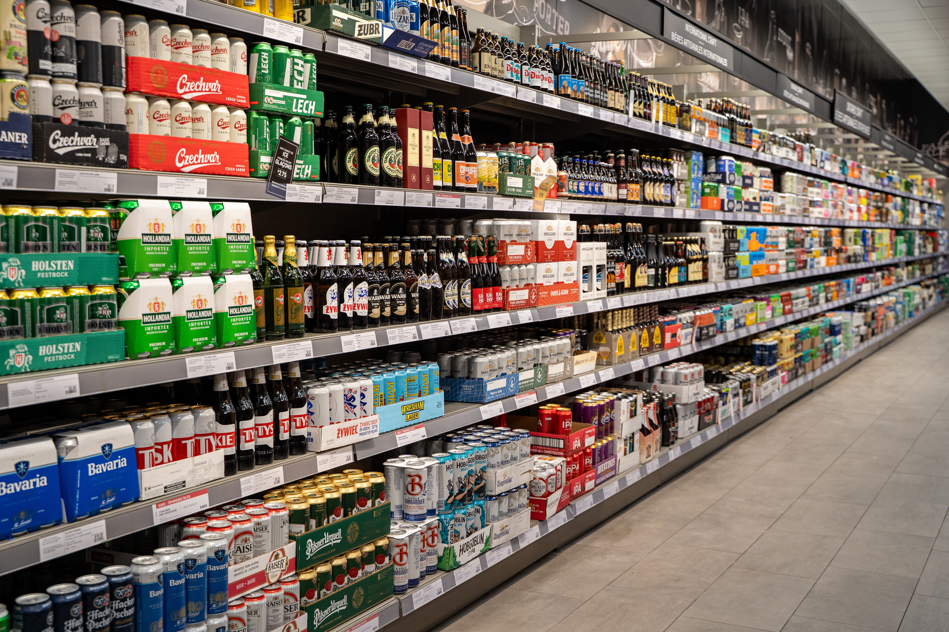 Regál s lahvovým a plechovkovým pivem v supermarketu