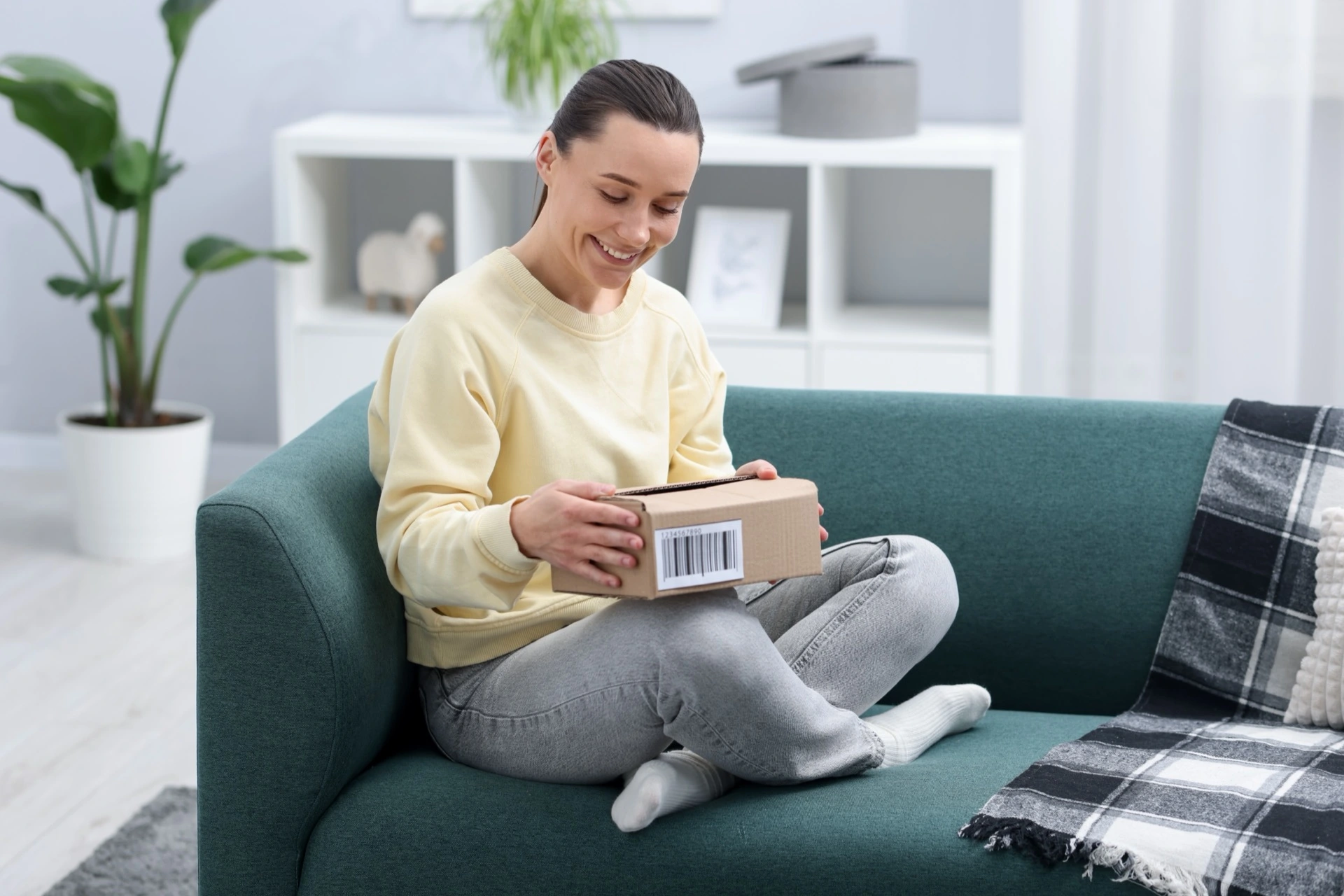 Žena doma otevírá doručený balík z e-shopu