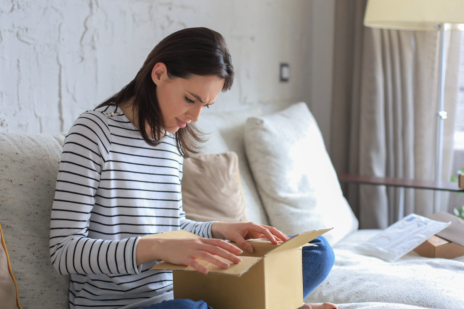 Žena doma rozbaluje kartonový balíček z e-shopu.