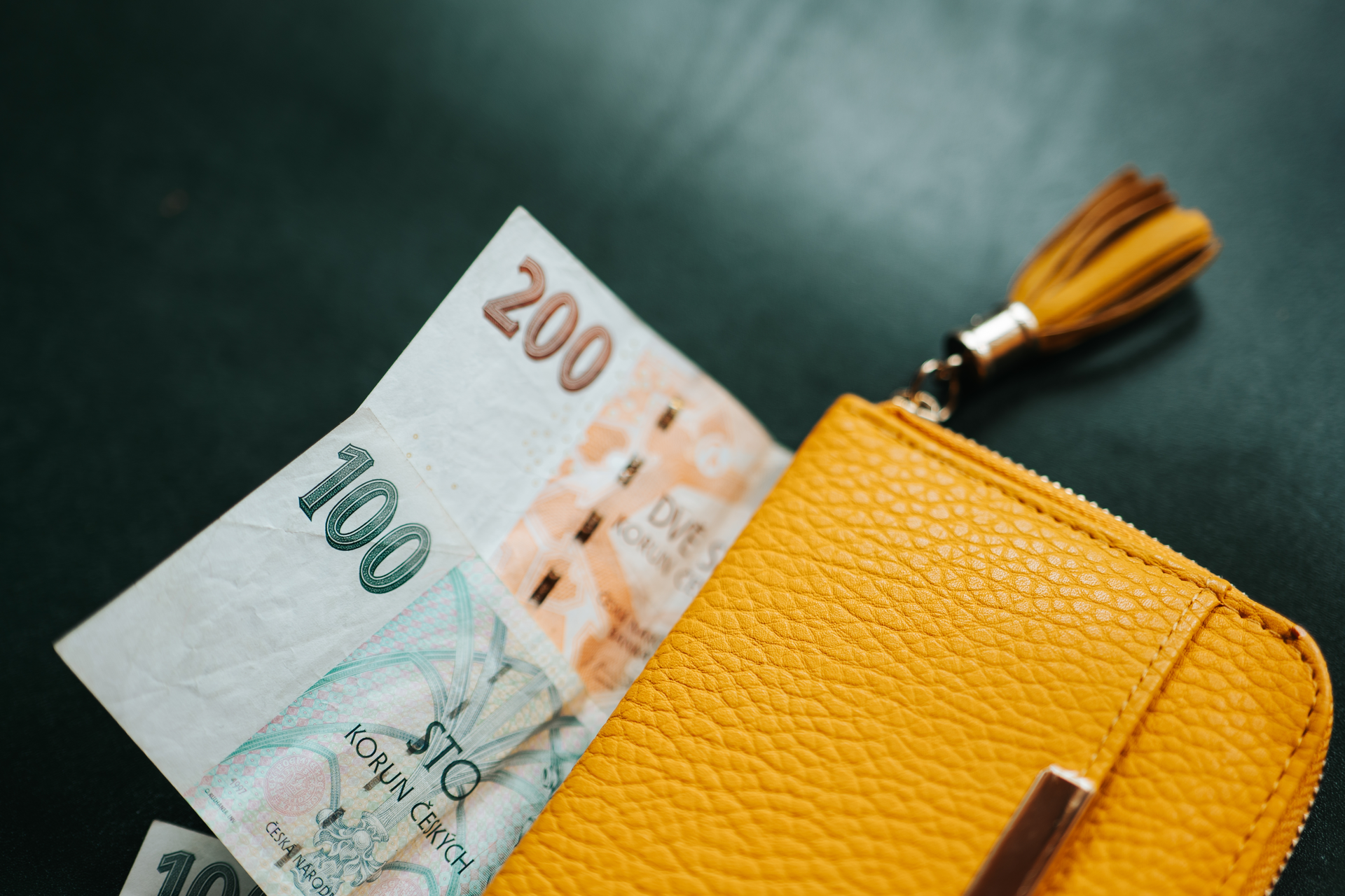 České bankovky 100 a 200 korun ve žluté peněžence
