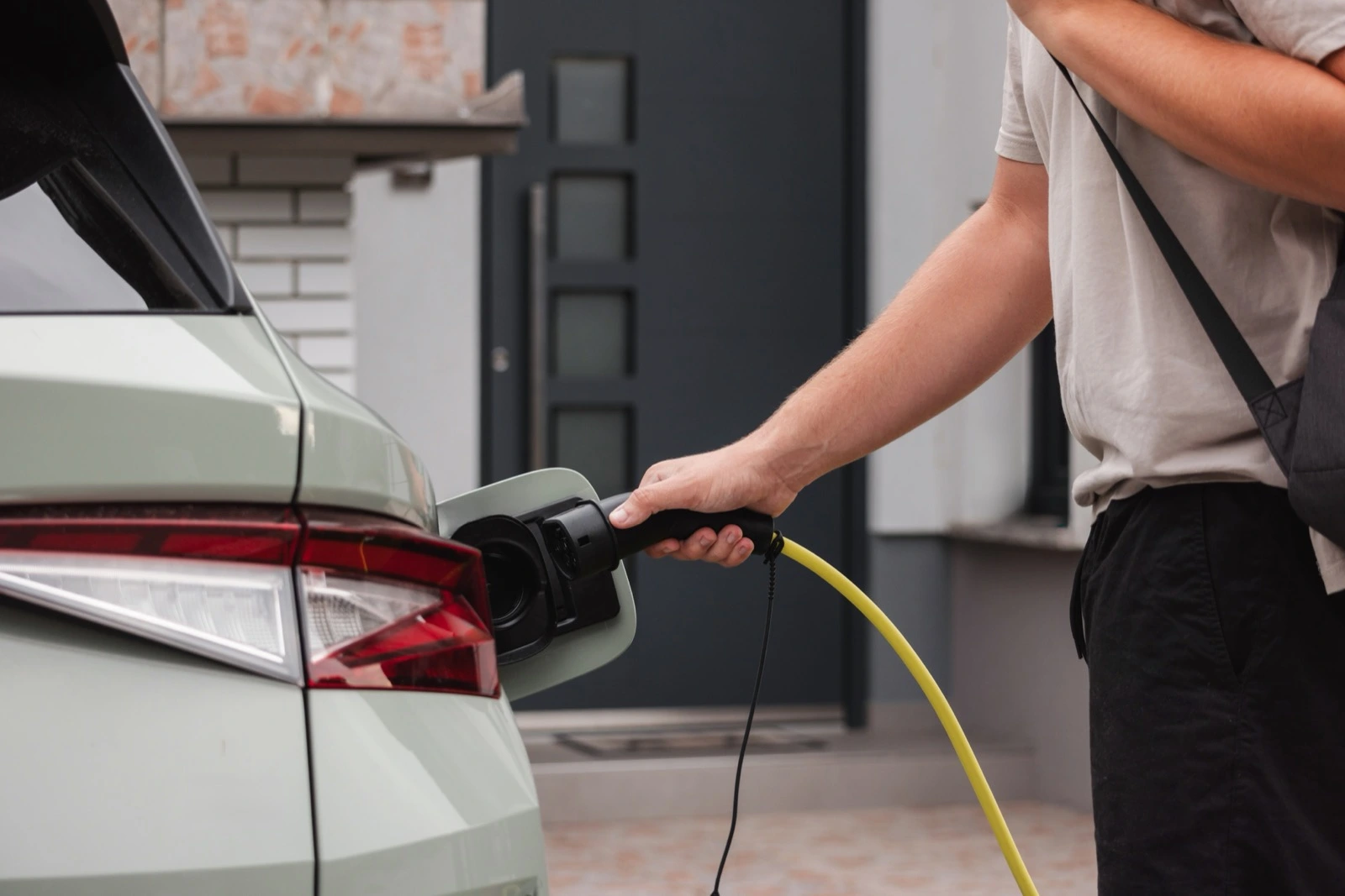 Muž nabíjí elektromobil u rodinného domu