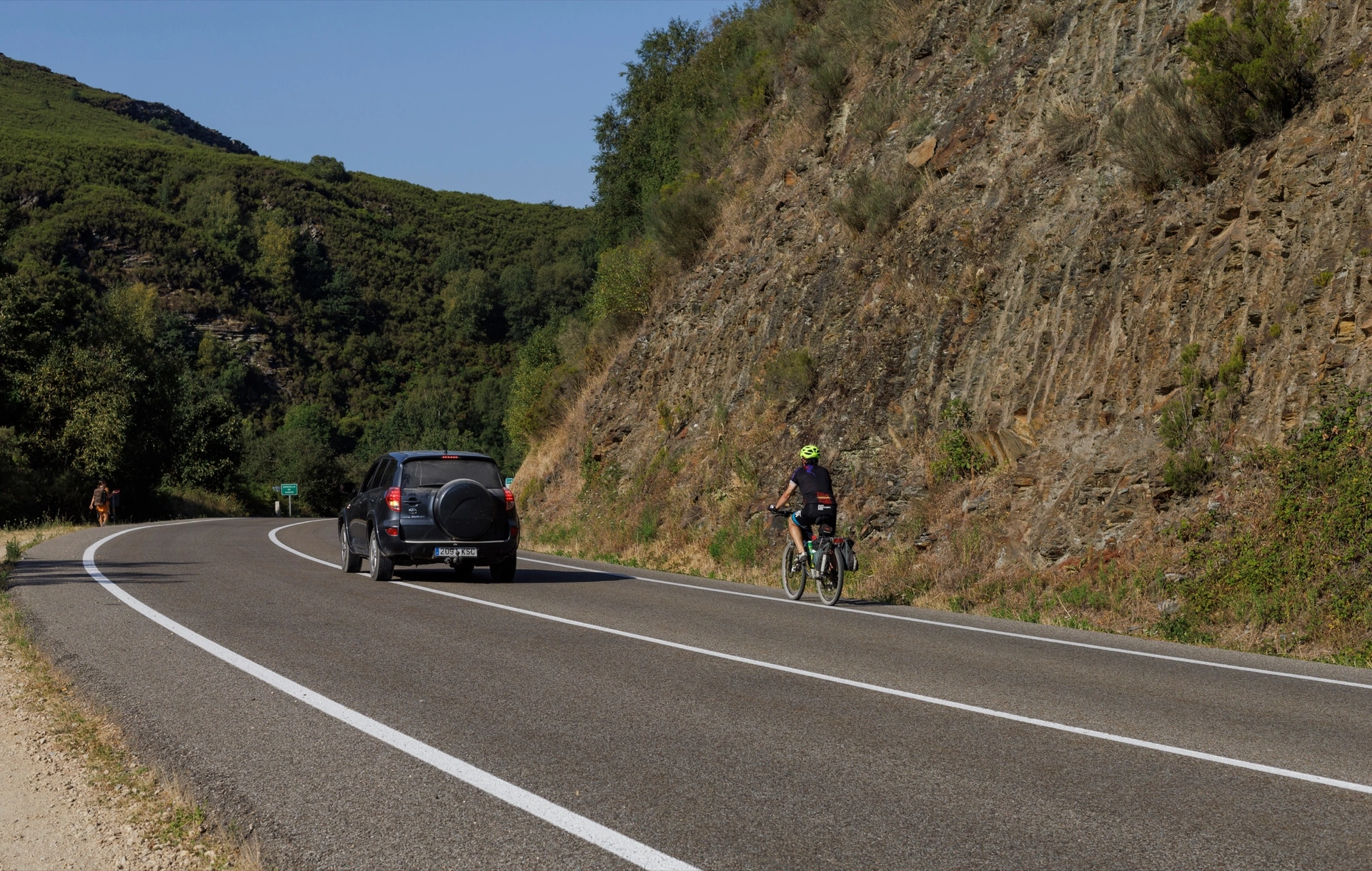 Terénní auto předjíždí cyklistu na horské silnici ve Španělsku