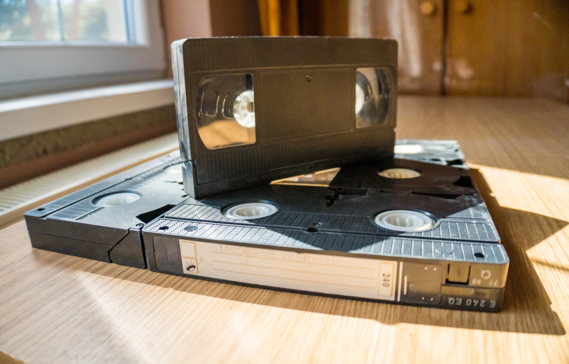 Staré VHS kazety s ručně psaným štítkem na stole u okna