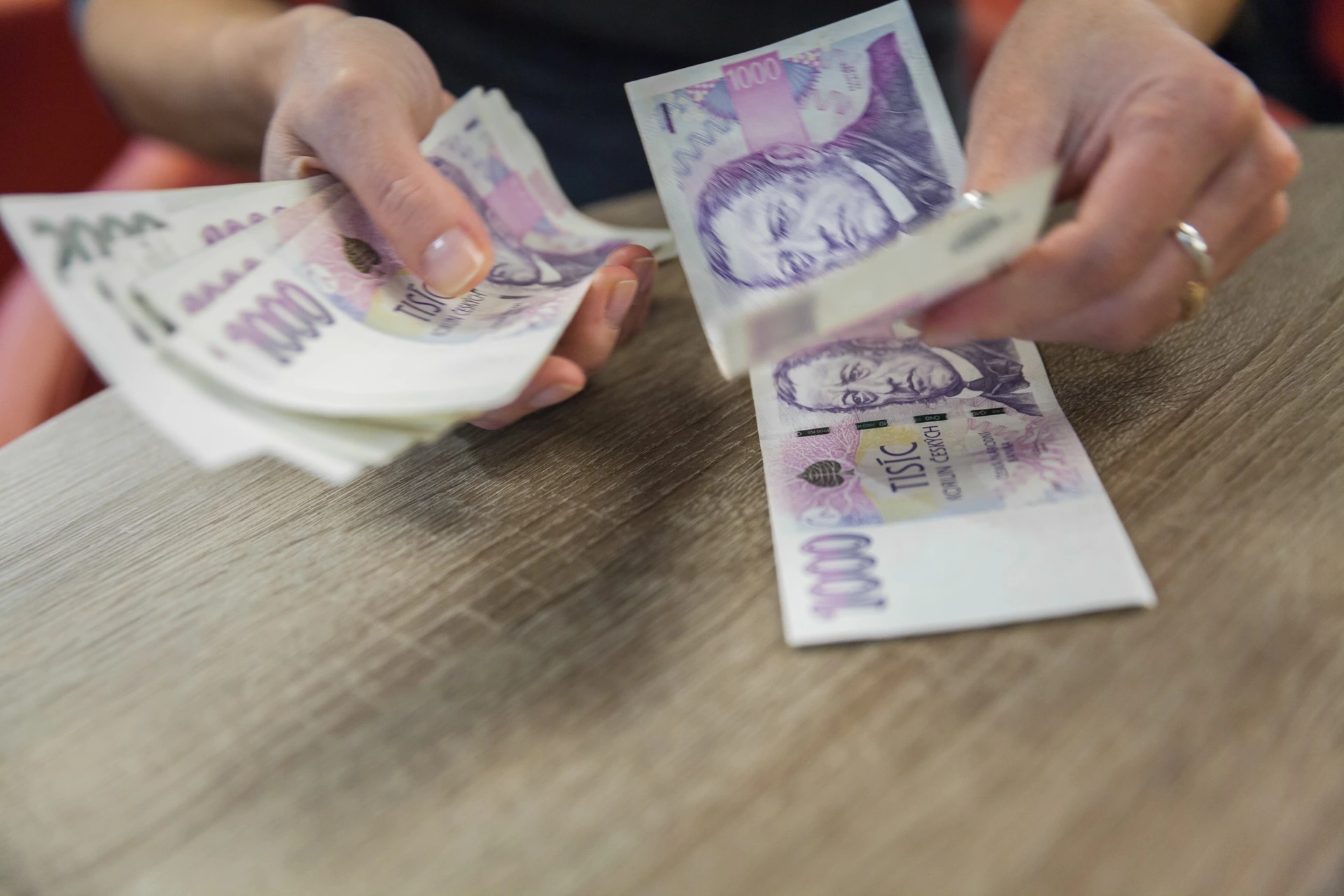 Ruce přepočítávají české tisícikorunové bankovky