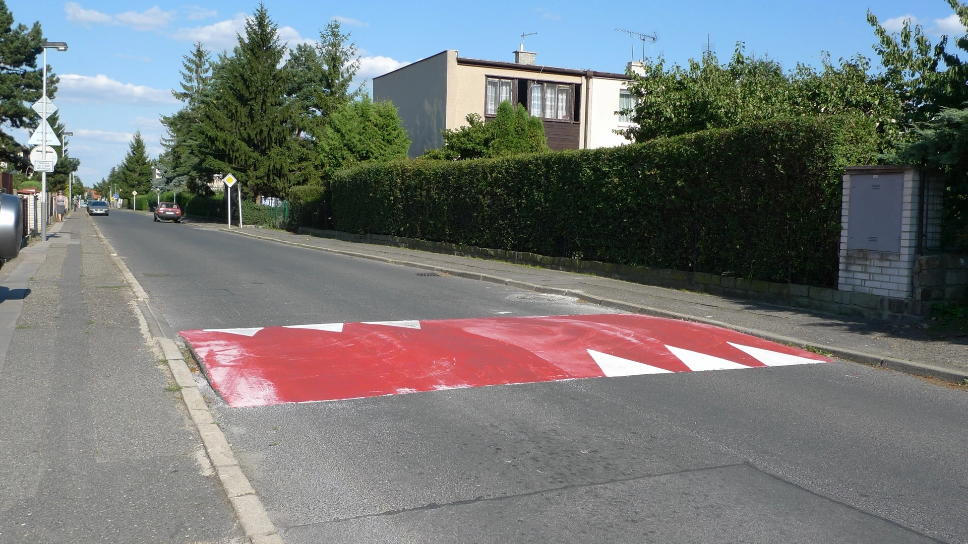 Zpomalovací práh s bílými trojúhelníky na ulici v Praze-Horních Počernicích